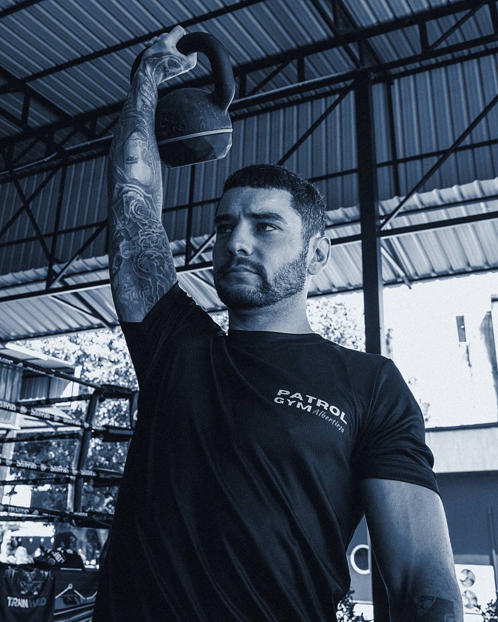 Kettlebell nyomás egy fedett edzőterületen, PatRol Gym mezben