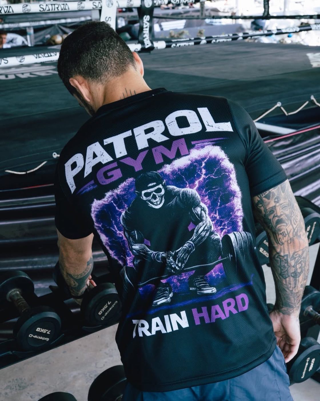 Kézisúlyzó-állvány a PatRol Gym termében, a háttérben a küzdősport-ring